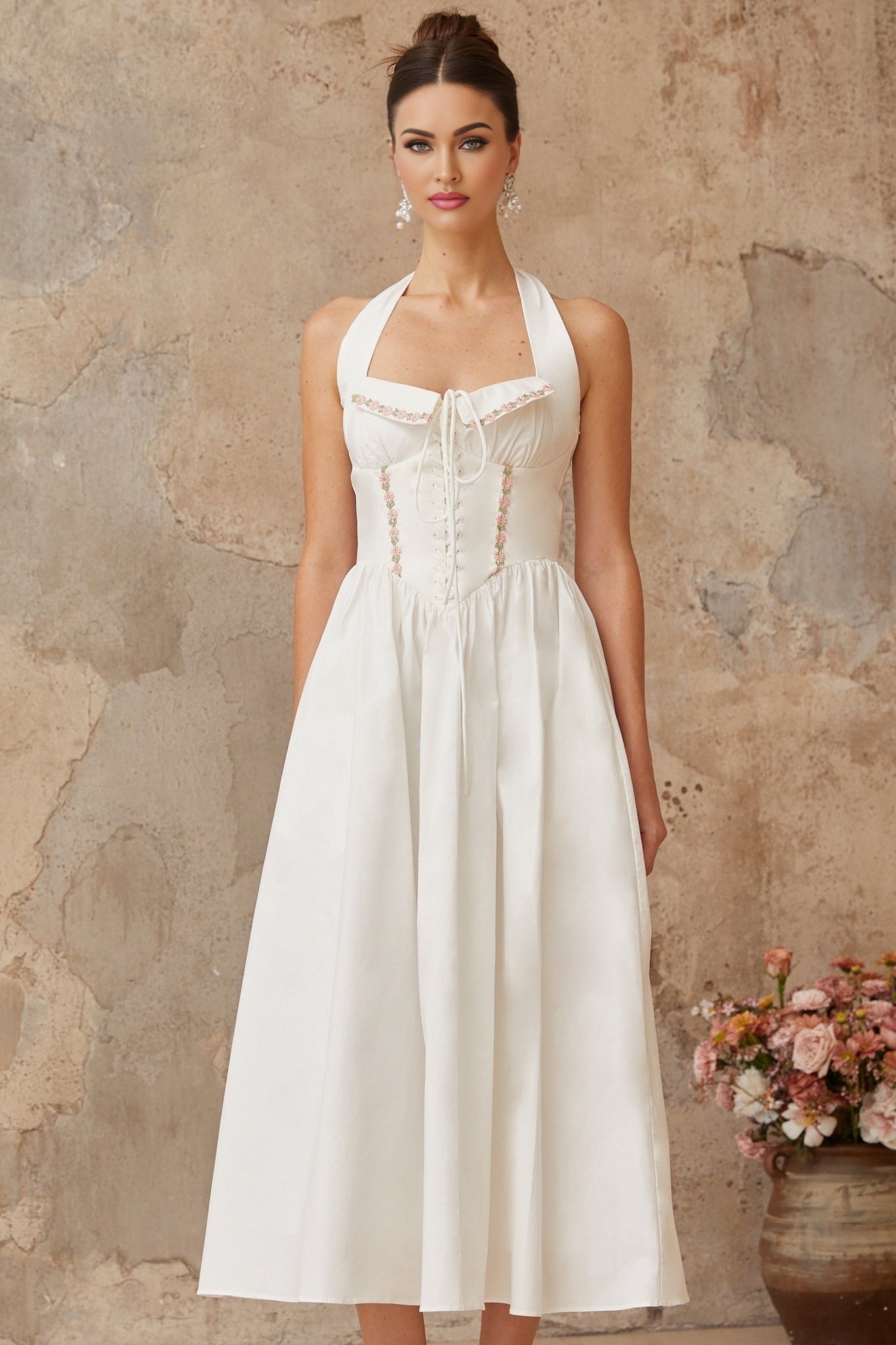 Woman wearing a white midi dress with lace up detail and shirred fabric standing in a relaxed pose