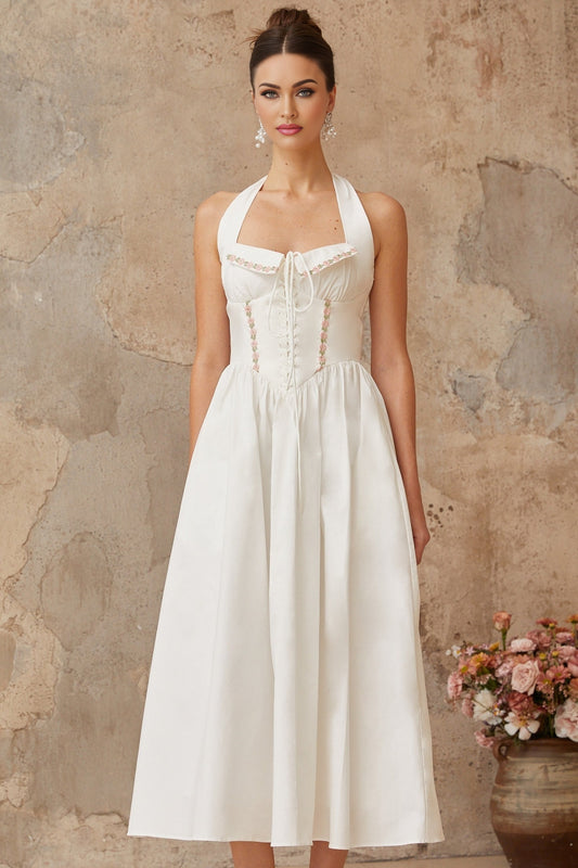 Woman wearing a white midi dress with lace up detail and shirred fabric standing in a relaxed pose