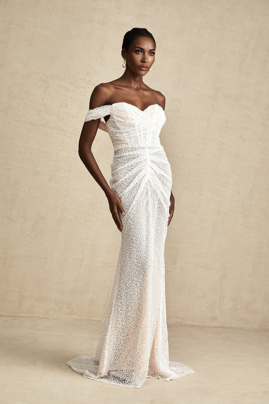 Woman wearing a white offshoulder maxi dress with embellishments named Margot