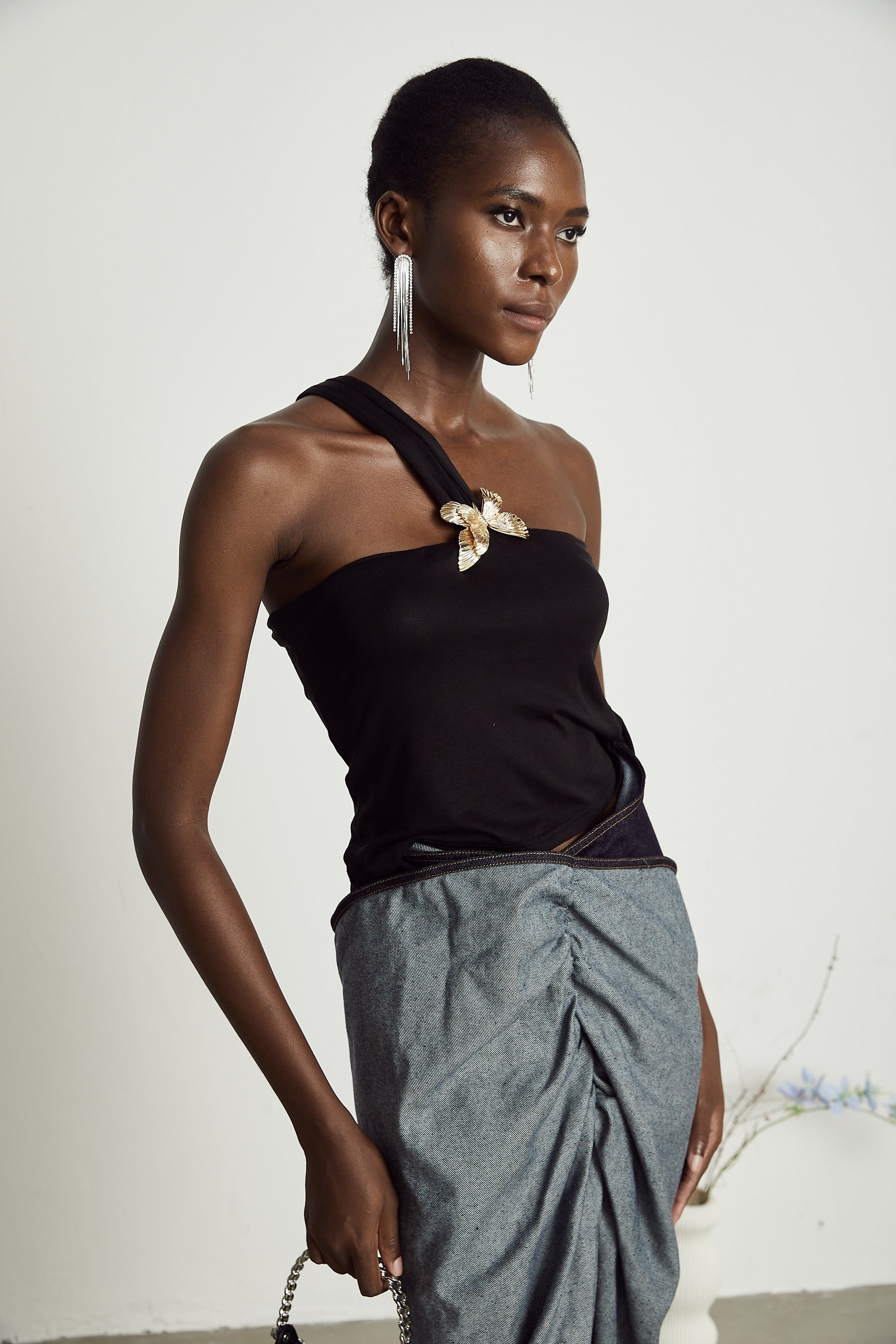 Woman wearing a white one shoulder top with ruffled detail