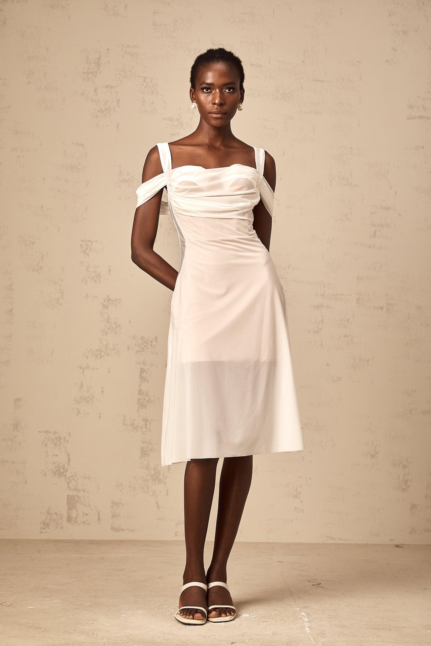 Woman wearing a white semi sheer ruched midi dress with gathered details standing in a neutral pose