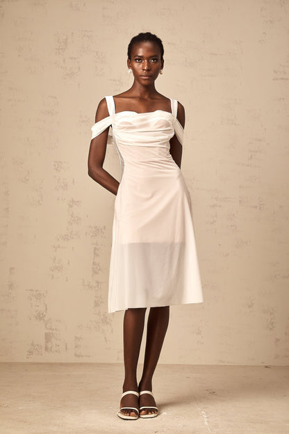 Woman wearing a white semi sheer ruched midi dress with gathered details standing in a neutral pose