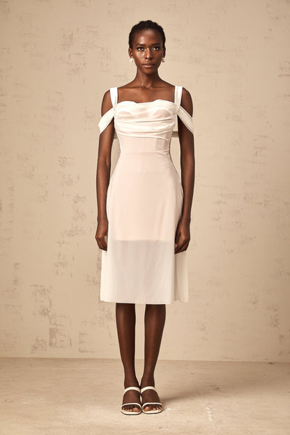 Woman wearing a white semi sheer ruched midi dress with gathered fabric details standing in a relaxed pose