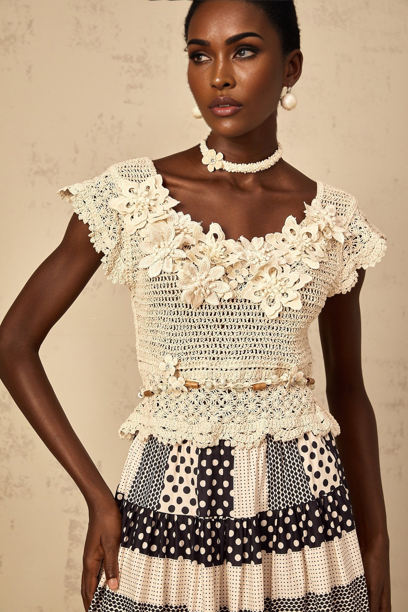 Woman wearing a white sleeveless knit top with colorful 3D floral beaded embellishments