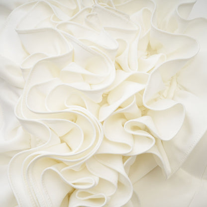 Woman wearing a white sleeveless top with delicate floral applique details along the neckline and shoulders