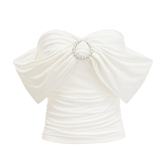 Woman wearing a white sleeveless top with gathered details at the neckline and shoulders