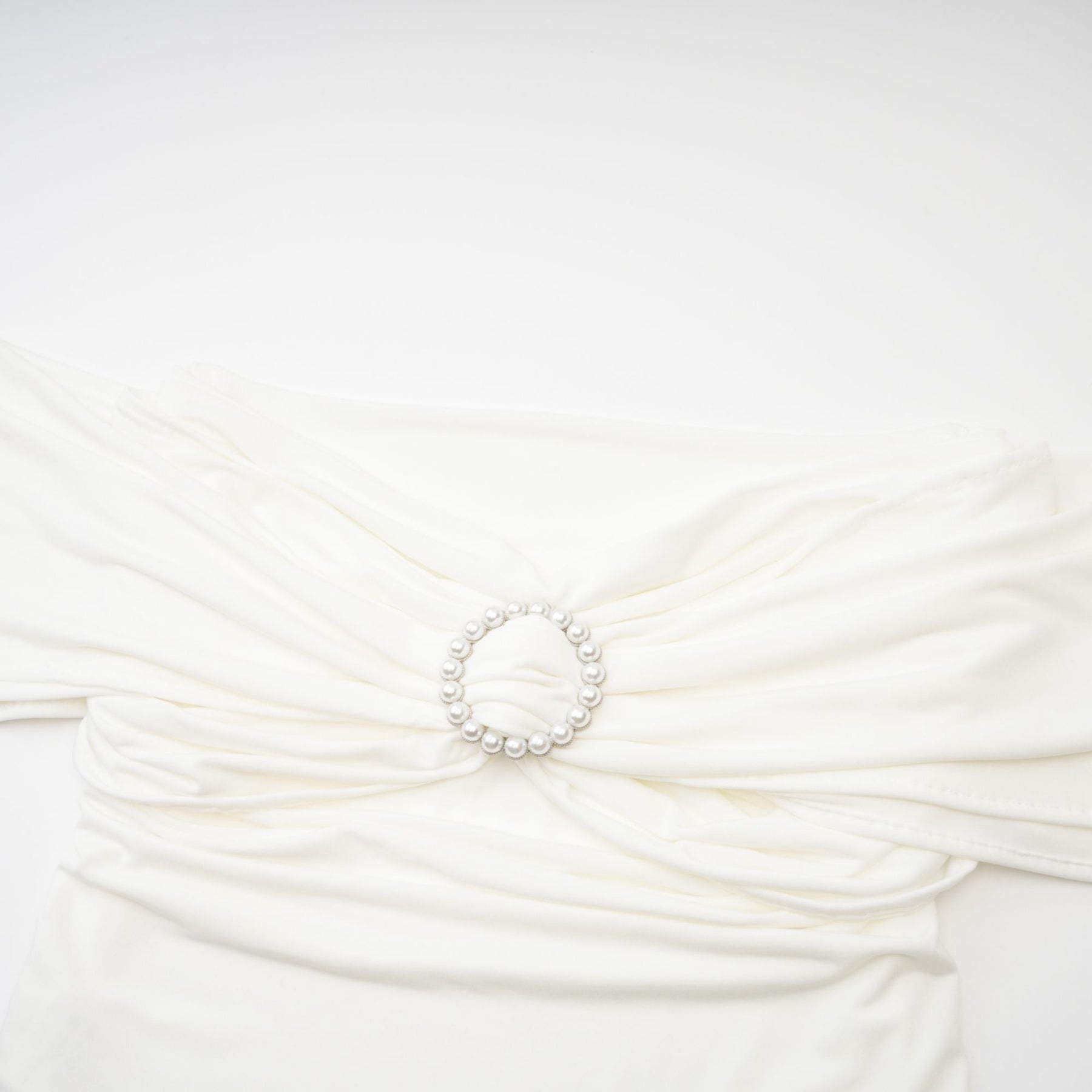 Woman wearing a white sleeveless top with gathered details on the neckline and shoulders