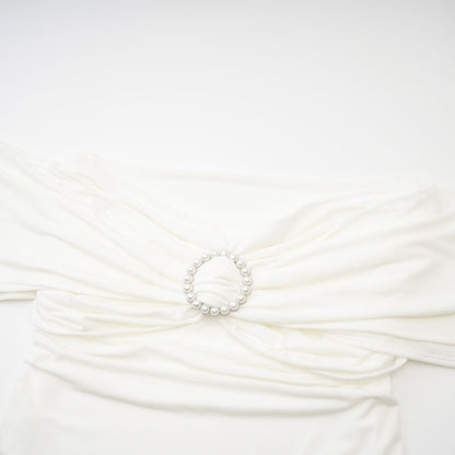 Woman wearing a white sleeveless top with gathered details on the neckline and shoulders