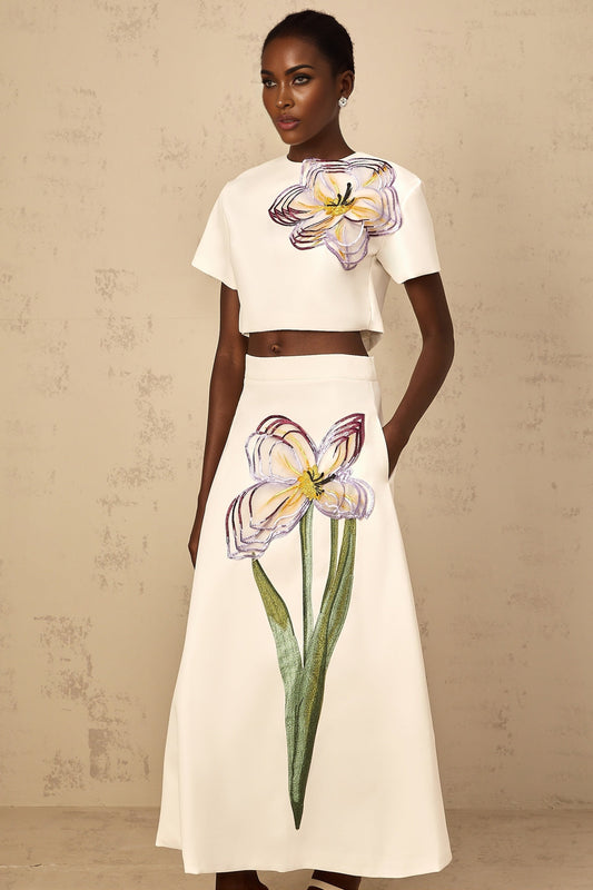Woman wearing a white twopiece outfit with sequin floral embroidery details on both top and bottom matching set