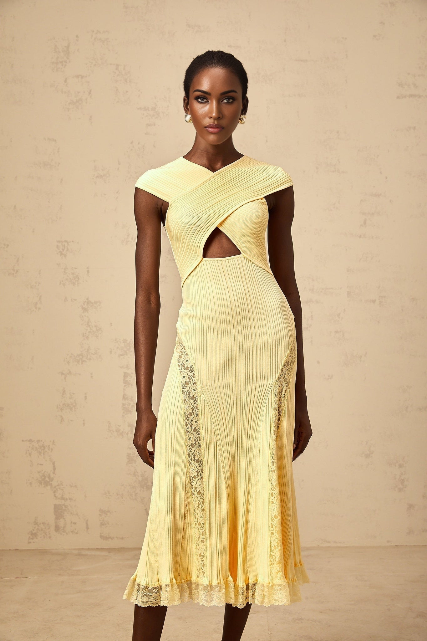 Woman wearing a yellow ribbed knit midi dress with lace panels standing in a neutral background
