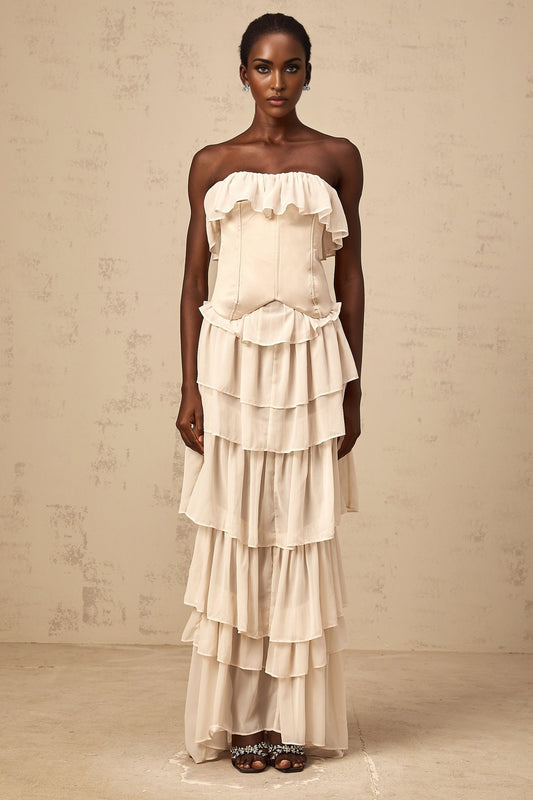 Woman wearing beige off shoulder dress with corset top and tiered skirt matching set