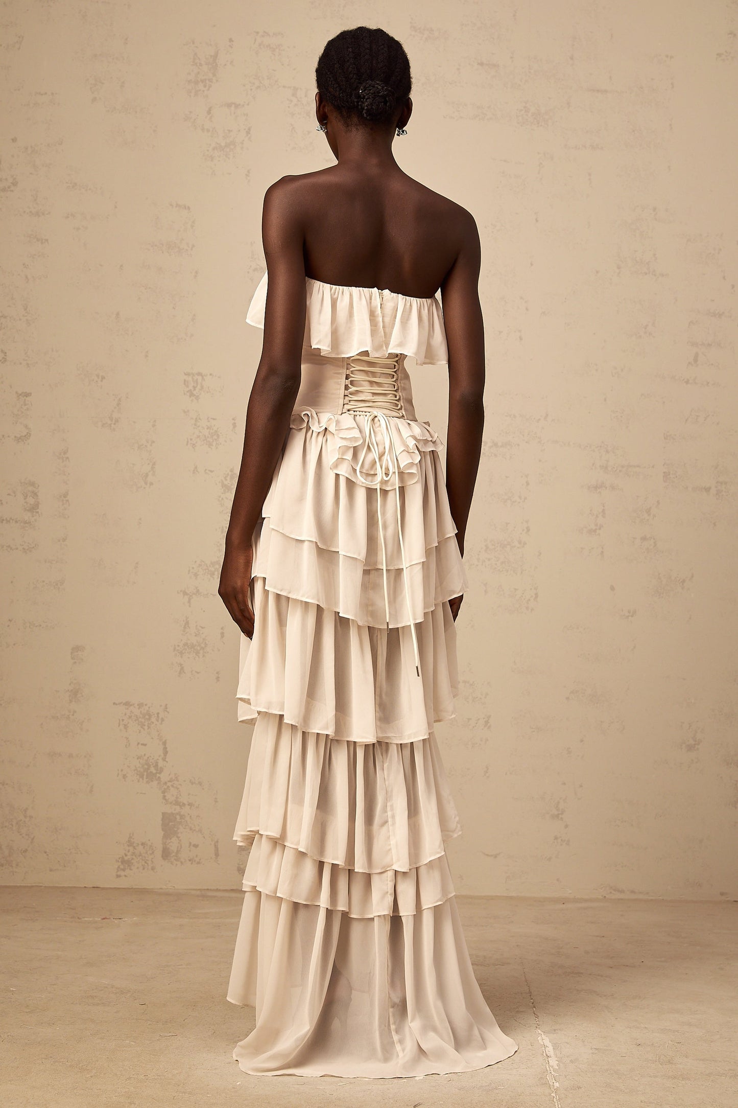 Woman wearing beige off shoulder dress with tiered skirt and matching corset top