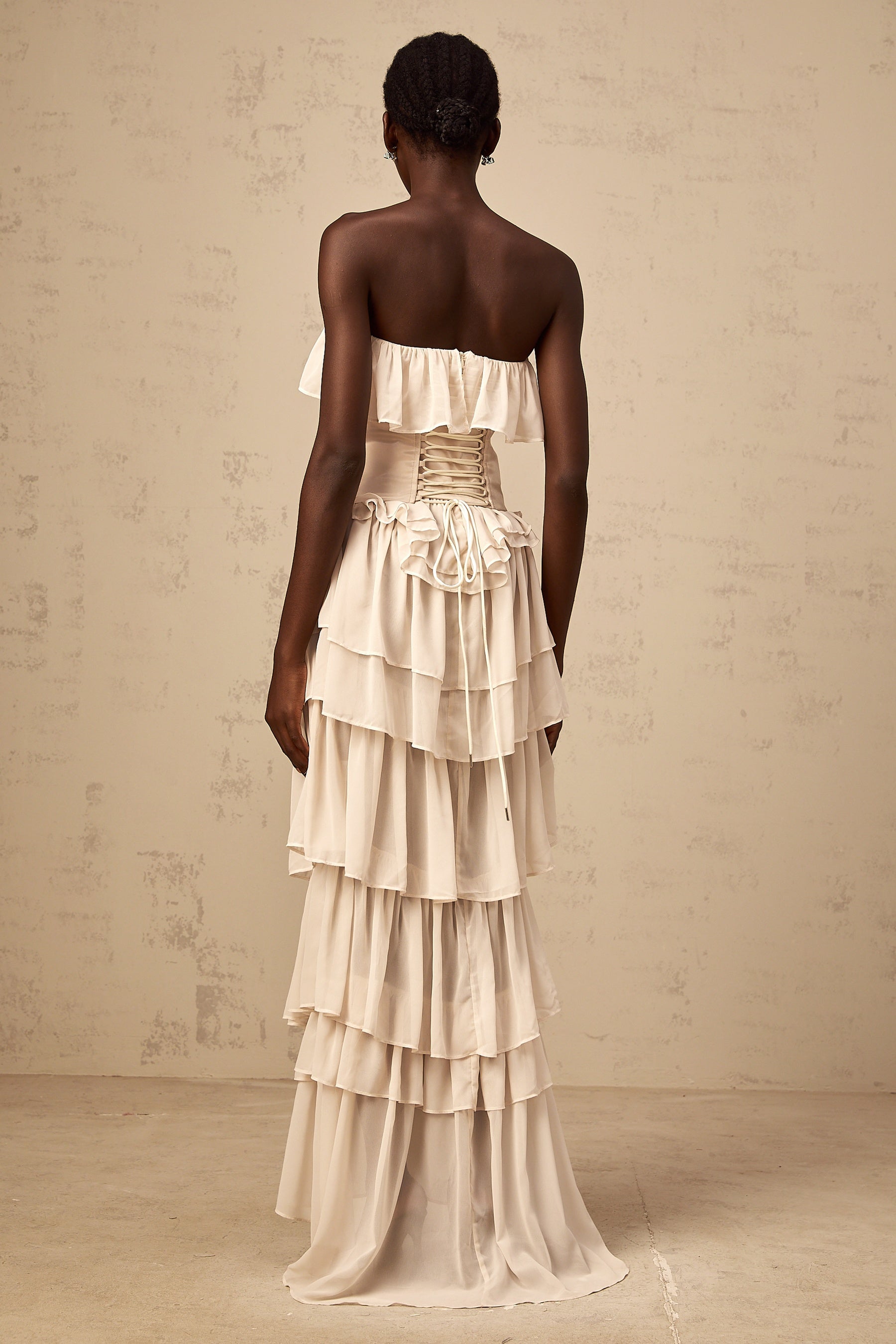 Woman wearing beige off shoulder dress with tiered skirt and matching corset top