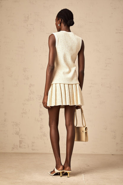 Woman wearing beige sequined knit vest top with matching skirt standing in casual pose
