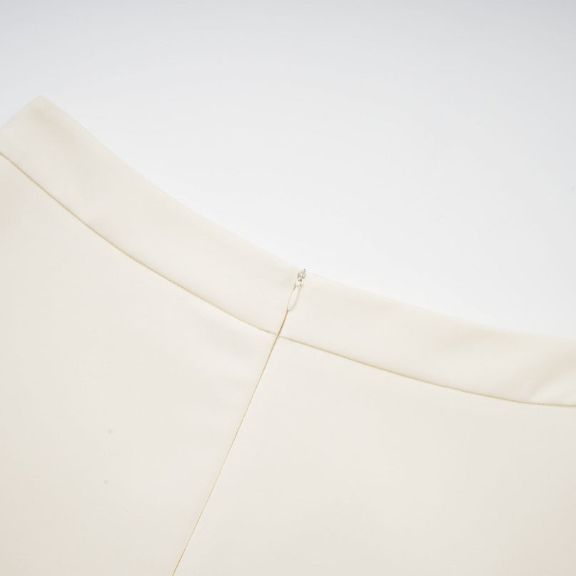 Woman wearing beige twopiece outfit with 3D floral petal details on top and matching skirt