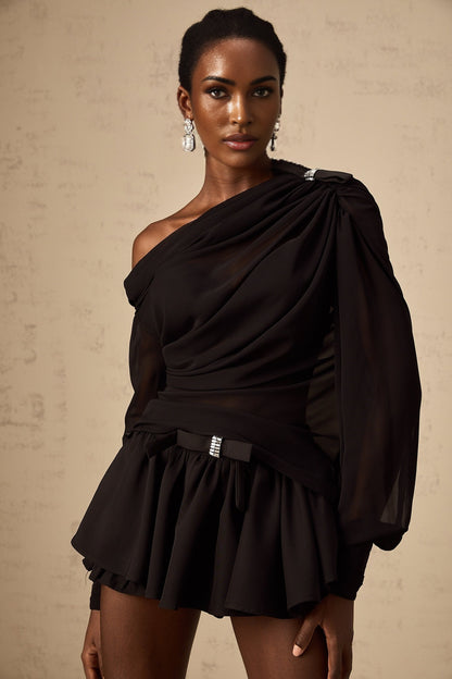 Woman wearing black asymmetric tulle blouse and matching skirt set