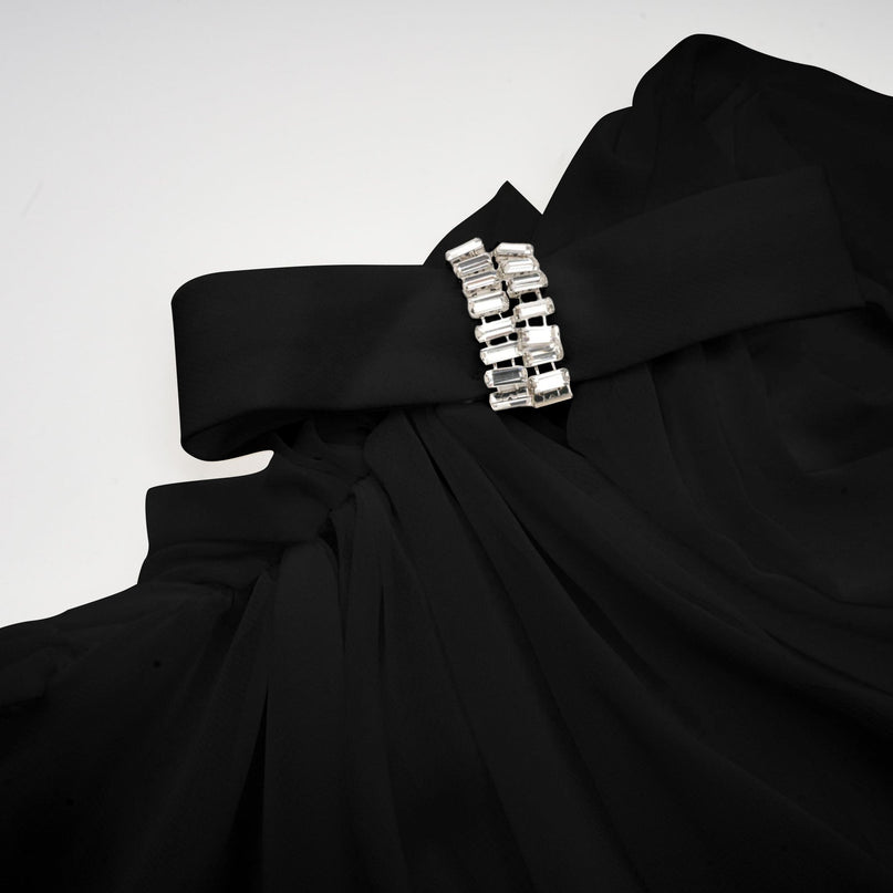 Woman wearing black asymmetric tulle blouse and matching skirt set