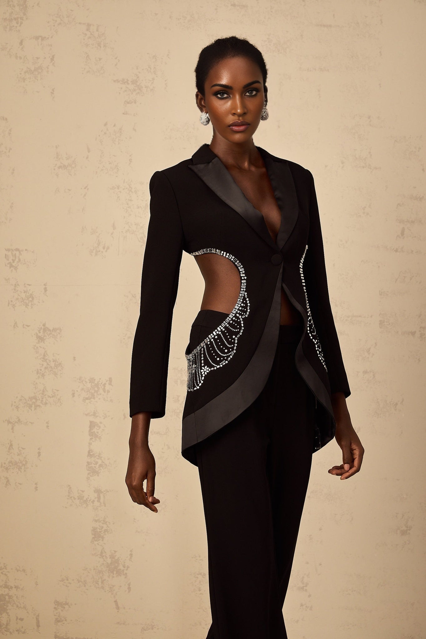 Woman wearing black blazer and trouser set with cutout details and embellishments