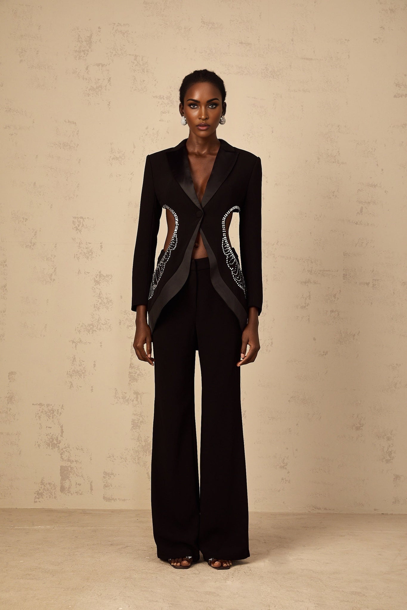 Woman wearing black blazer and trousers set with cutout details and embellishments elegant formal outfit