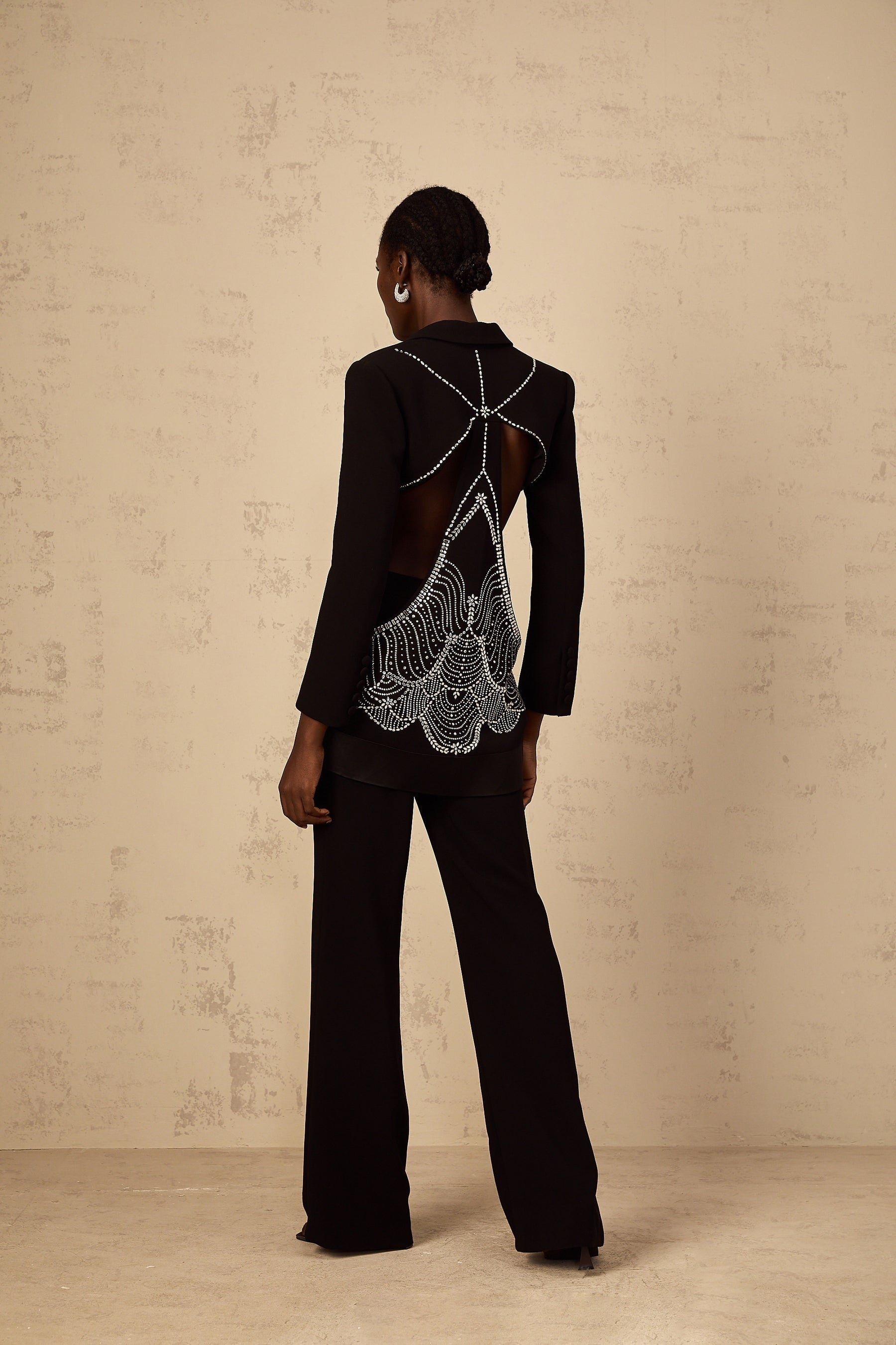 Woman wearing black blazer and trousers set with cutout details and embellishments