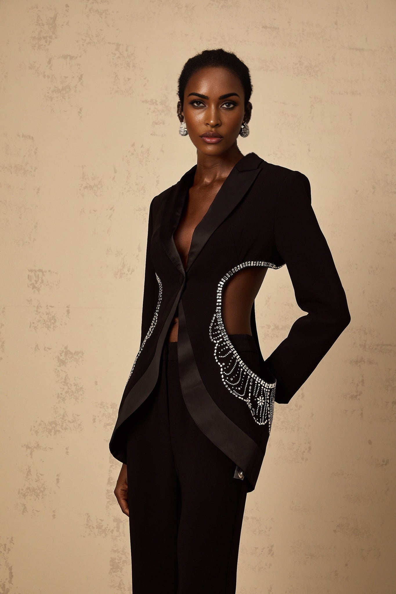 Woman wearing black blazer and trousers set with cutout details and embellishments