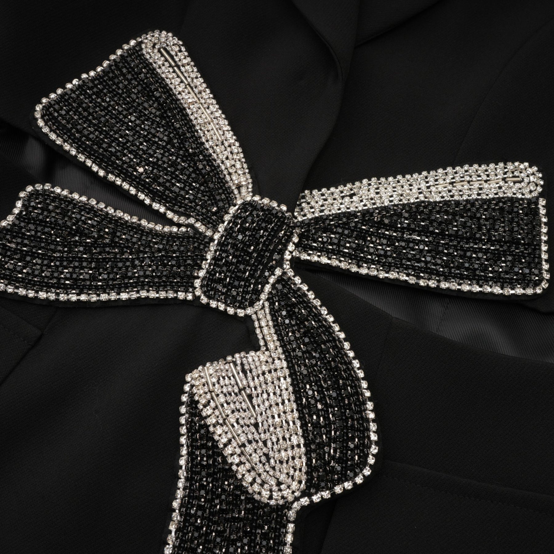 Woman wearing black blazer with cutout details and decorative bow accent