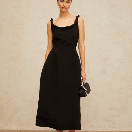 Woman wearing black braided puff sleeve midi dress with fitted bodice and flowing skirt