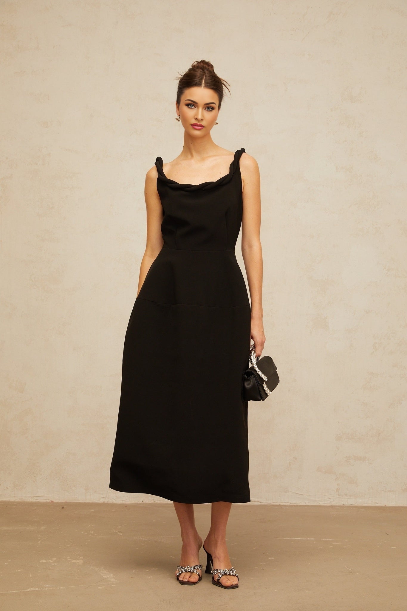 Woman wearing black braided puff sleeve midi dress with fitted bodice and flowing skirt