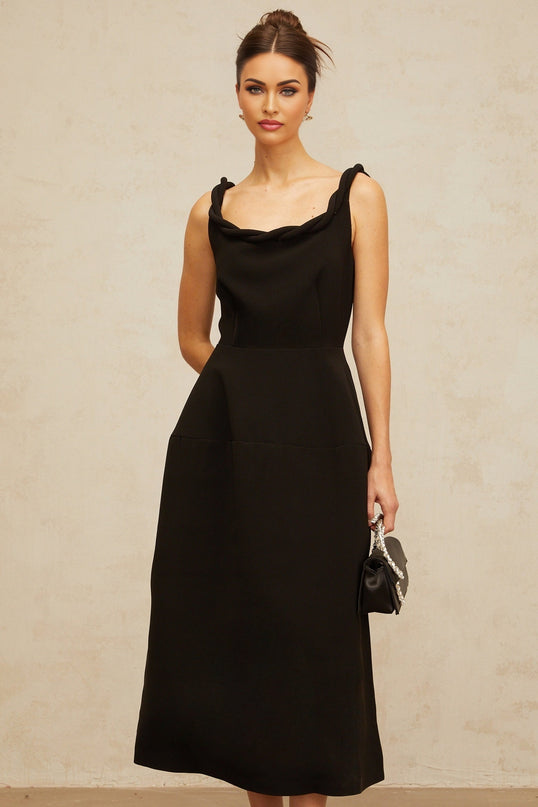 Woman wearing black braided puff sleeve midi dress with fitted bodice and full skirt