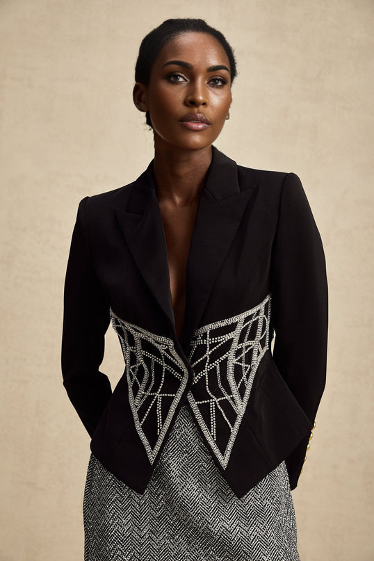 Woman wearing black fitted jacket with embellished details and cinched waist