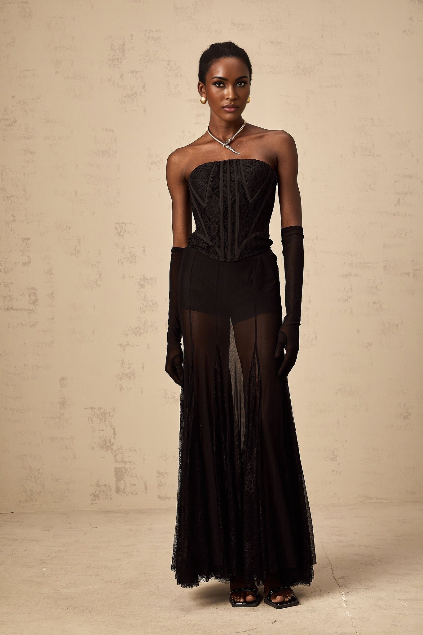 Woman wearing black floral lace matching set consisting of corset skirt and gloves