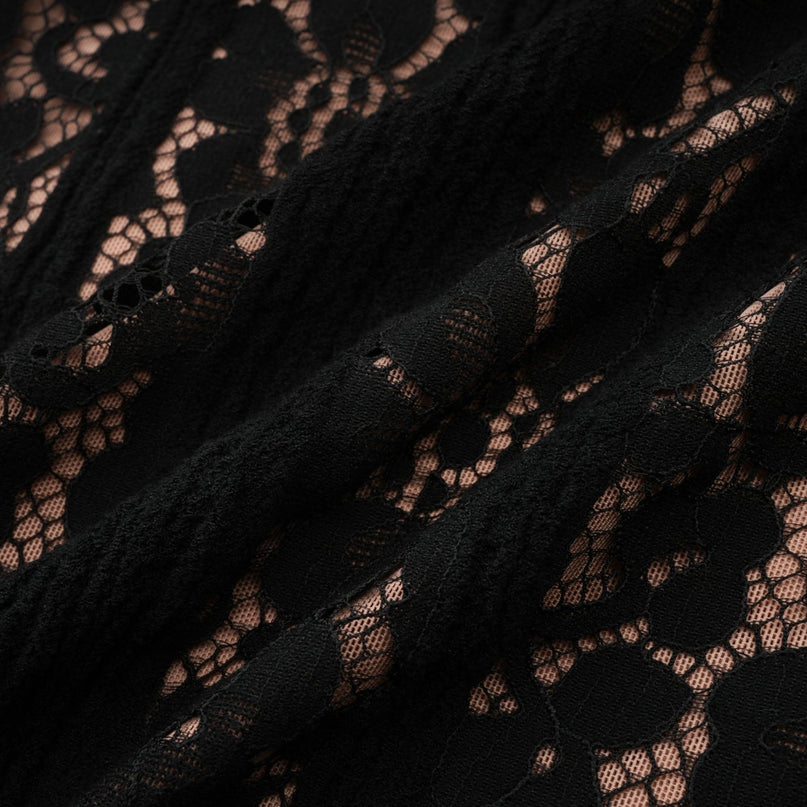 Woman wearing black floral lace midi dress with flared cuffs standing in elegant pose