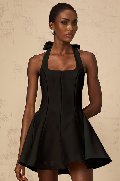 Woman wearing black halterneck mini dress with bow detail at neck