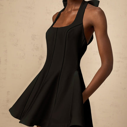 Woman wearing black halterneck mini dress with bow detail at neckline
