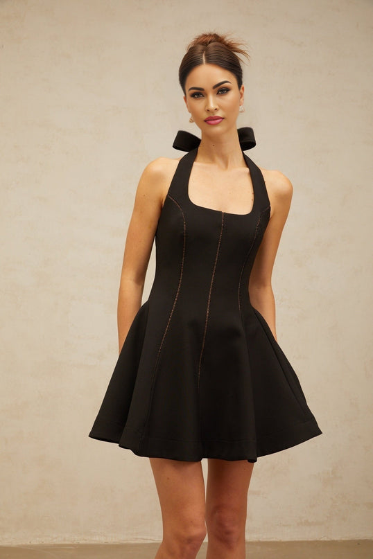 Woman wearing black halterneck mini dress with bow detail at neckline