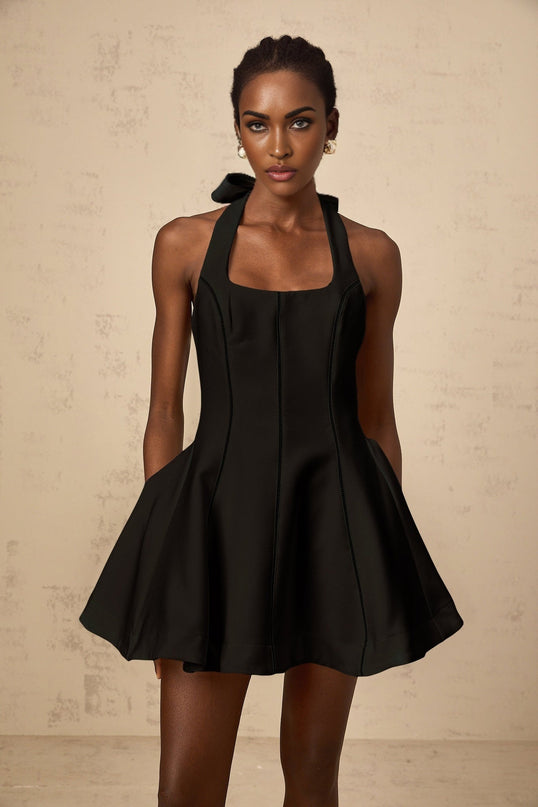 Woman wearing black halterneck mini dress with bow detail
