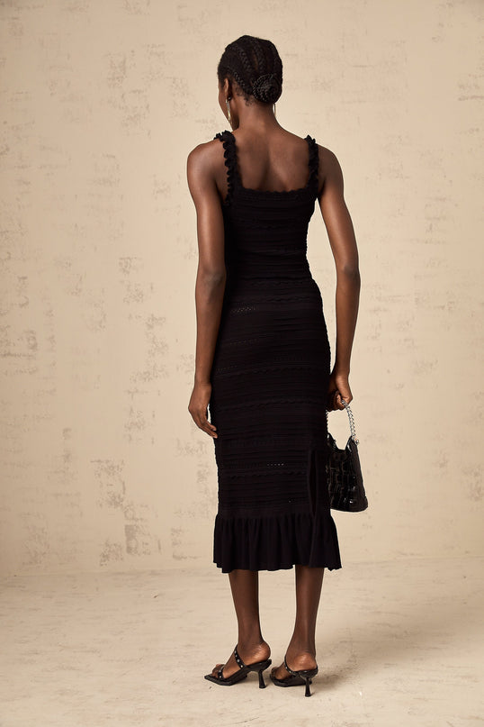 Woman wearing black knitted matching set with ruffled top and skirt