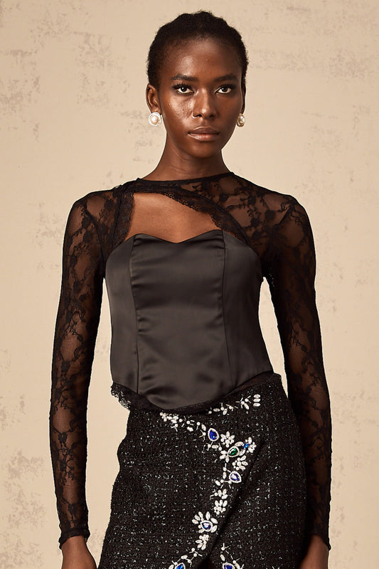 Woman wearing black lace top with cutout details sleeveless blouse with intricate floral pattern