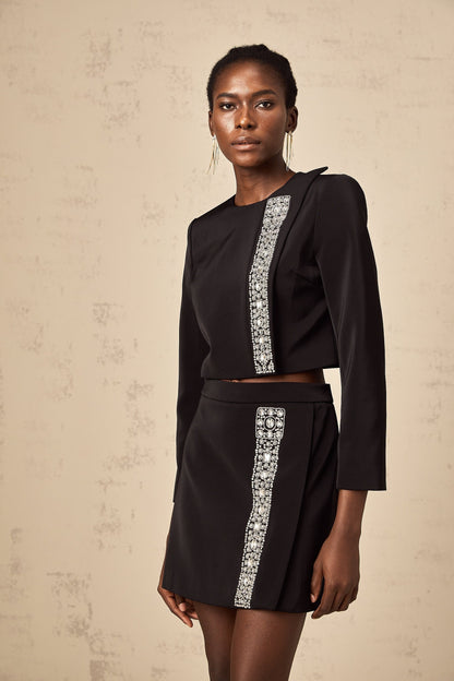 Woman wearing black matching set consisting of crystalembellished top and skirt named Nadia