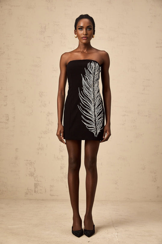 Woman wearing black off shoulder mini dress with feather embellishments