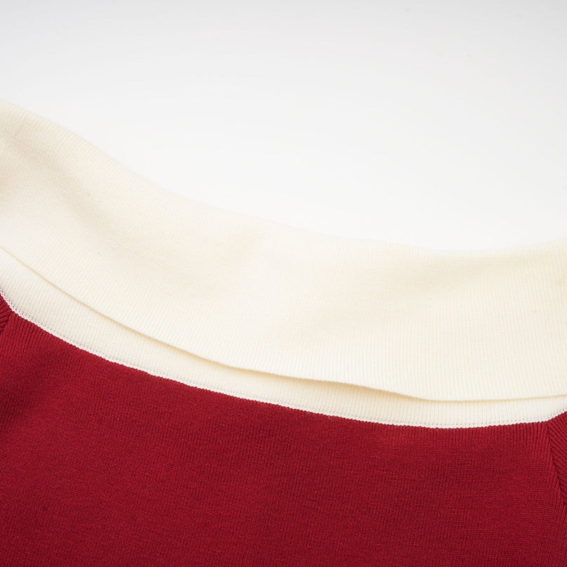 Woman wearing black offshoulder knit midi dress standing against plain background