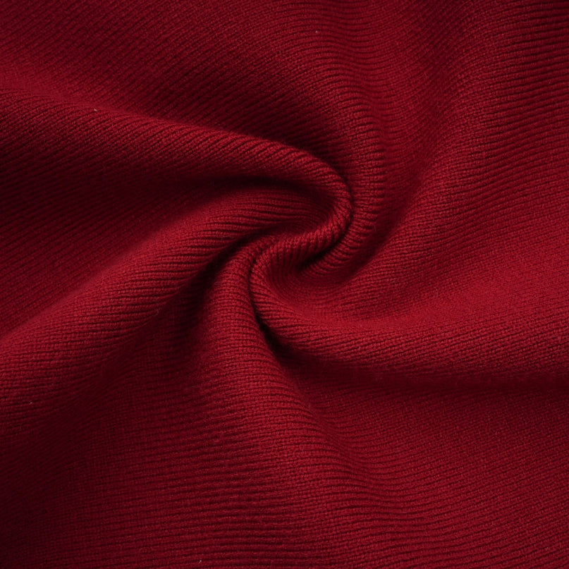 Woman wearing black offshoulder knit midi dress with long sleeves standing against plain background