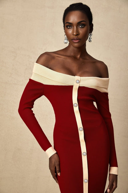 Woman wearing black offshoulder knit midi dress with long sleeves standing against white background