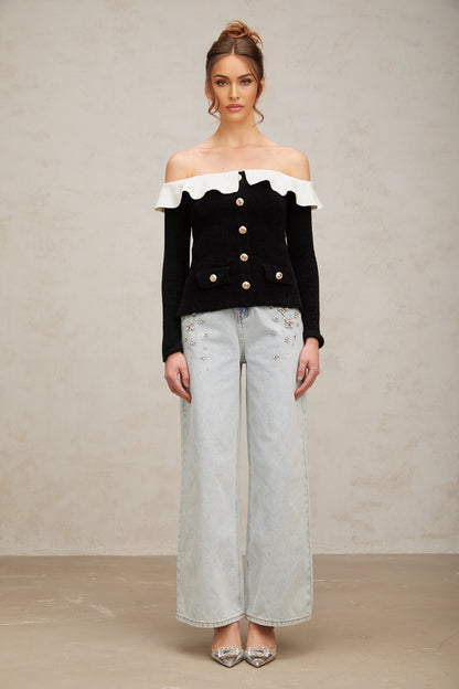 Woman wearing black offshoulder top with ruffled neckline