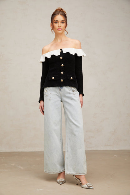 Woman wearing black offshoulder top with ruffled neckline
