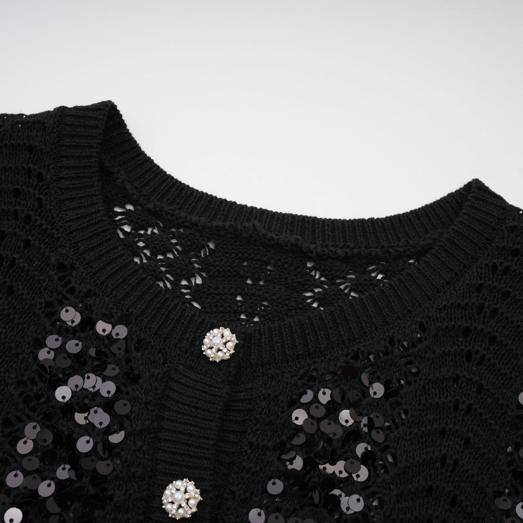 Woman wearing black sequined cardigan and matching skirt set with crochet knit pattern