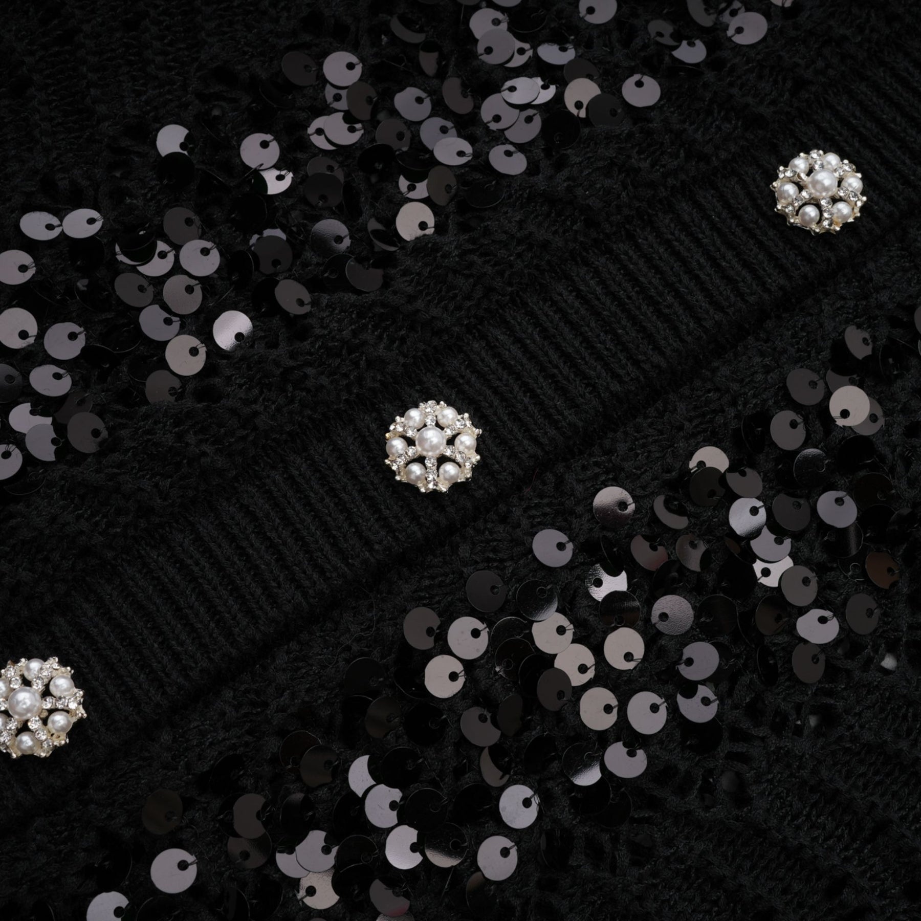 Woman wearing black sequined cardigan and matching skirt set with crochet knit texture
