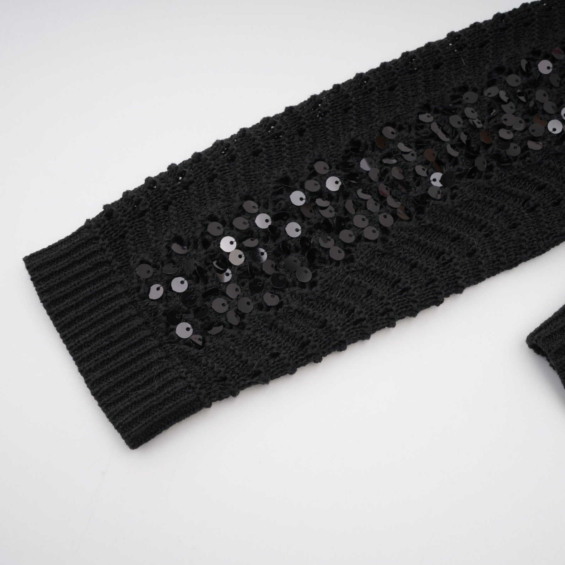 Woman wearing black sequined crochet cardigan and matching skirt set with sparkly texture
