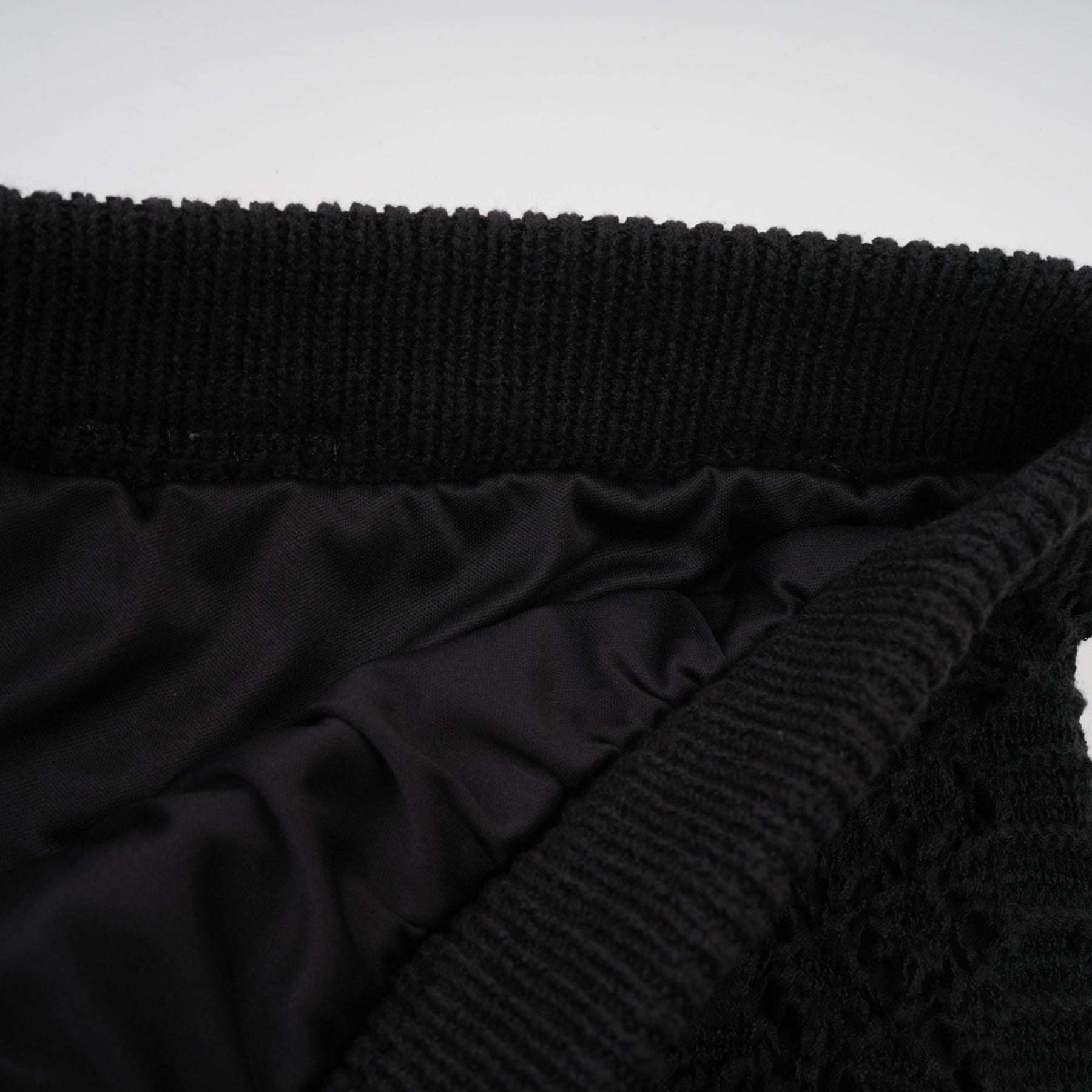 Woman wearing black sequined crochet knit cardigan and matching skirt set