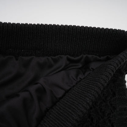 Woman wearing black sequined crochet knit cardigan and matching skirt set